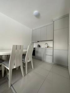 乌罗舍瓦茨4-YOU Apartment的白色的厨房配有白色的椅子和桌子