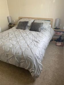 ScratbyDuffy's Den - Parkdean California Cliffs - Fulmar 45的卧室内的一张带白色床单和枕头的床
