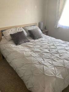 ScratbyDuffy's Den - Parkdean California Cliffs - Fulmar 45的卧室内的一张带两个枕头的白色床