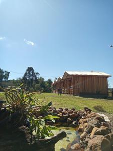 Ametista do SulHotel cabanas bom Jesus的小木屋和大楼前的池塘