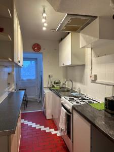 布罗姆利Double Room With Free WiFi Keedonwood Road的厨房配有白色橱柜和红色瓷砖地板。