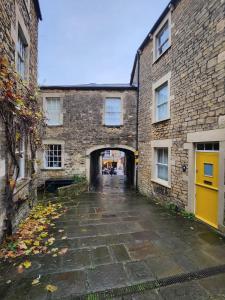 弗罗姆Rose & Star Cottage的两座砖砌建筑之间的一条小巷,有黄色的门