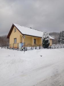 Nowa WieśSielankowy Domek的雪中带栅栏的房子