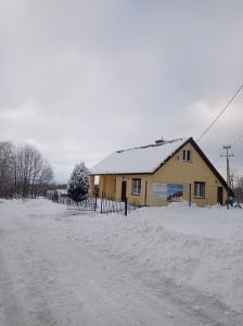 Nowa WieśSielankowy Domek的雪 ⁇ 路上的黄色房子,有雪盖屋顶