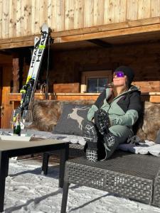 阿尔卑巴赫Ferienwohnung Kast'l的坐在长凳上的女人,坐在桌子上,滑雪板