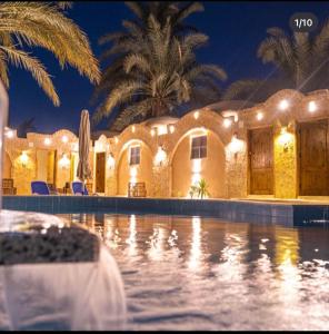 锡瓦Siwa Palace Lodge的一座晚上设有游泳池的房子
