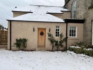 LoanheadQuaint self contained cottage near Edinburgh.的雪中有一扇门的房子