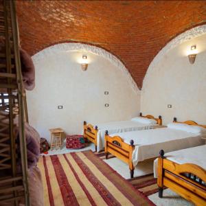 锡瓦Siwa Palace Lodge的一间设有两张床和砖墙的房间