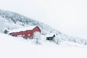 ØyerHafjell Farmhouse的山边的红色谷仓,有雪