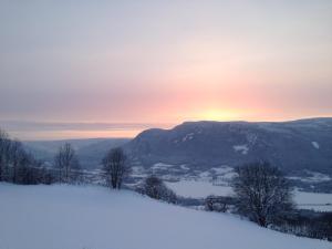 ØyerHafjell Farmhouse的一座雪覆盖的山丘,背面是日落