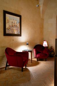 马泰拉Lo Stemma Luxury Boutique Hotel的客厅配有2把红色椅子和桌子