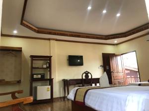 琅勃拉邦Xayana Home Villas的卧室配有一张床,墙上配有电视。
