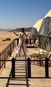 瓦迪拉姆Wadi Rum Mars Camp的沙漠木板路上穿白色衣服的女人