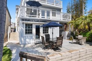 圣地亚哥Stunning Beach Home - Steps to the Bay,Beach, &Boardwalk w Grill & Patios的庭院配有桌椅和遮阳伞。