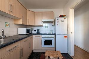 吉林汉姆Cosy Retreat - SmartTV and Wi-Fi的厨房配有木制橱柜和白色冰箱。