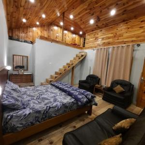 BālākotThe Kunhar Beach Cottage At Country Club Balakot的一间卧室设有一张床、一张沙发和木制天花板