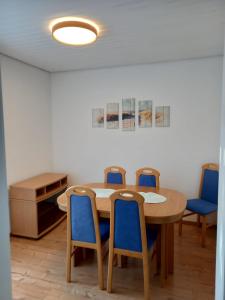 格恩斯巴赫Schöne Ferienwohnung in Gernsbach的一间设有桌子和四把蓝色椅子的房间