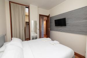 阿萨哥Apartment Forum IV的卧室配有白色的床和墙上的电视。