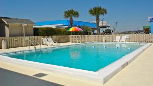 彭萨科拉Motel 6 - Pensacola West的一个带椅子和遮阳伞的游泳池