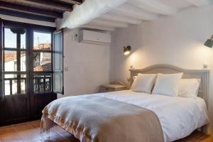 Casas del CastañarCasa rural la grande的卧室设有一张白色大床和一扇窗户。