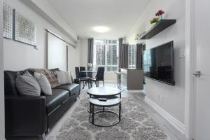 多伦多Simply Comfort Suites - One plus Den Apartment with Scotiabank Arena View的客厅配有黑色沙发和桌子