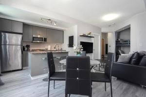 多伦多Simply Comfort Suites - One plus Den Apartment with Scotiabank Arena View的厨房以及带桌椅的起居室。
