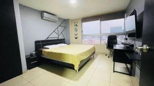 瓜亚基尔Five Stars Suites - Kennedy - Guayaquil的一间卧室配有一张床、一张书桌和一个窗户。