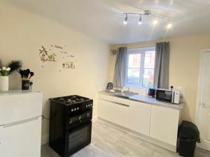 赫尔Kisobi Home Bedroom 2的厨房配有白色橱柜和黑炉。