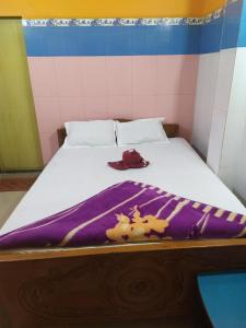 迪卡PAYEL LODGE的一张带紫色毯子和帽子的床