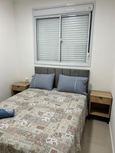 戈亚尼亚Apartamento perfeito em bairro nobre por insta @thiagojacomo的一间卧室配有一张带蓝色枕头的床和一扇窗户。