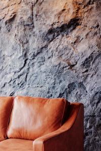 日落洞Urban Suites, Autograph Collection by Stellar ALV的石墙前的棕色皮沙发