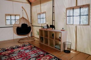TangkubanperahuLuxury Deck Cabin的客房设有吊床、椅子和地毯。