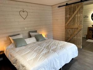 斯图蒙Ambiance boisée Moustier的卧室配有一张白色大床,墙上有心