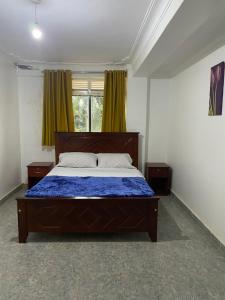 NamugongoIngrid's Place - Namugongo的一间卧室配有一张带蓝色棉被的床和窗户。