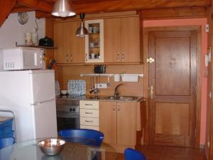 莱斯卡拉Apartamentos Olimpia的厨房配有木制橱柜和白色冰箱。