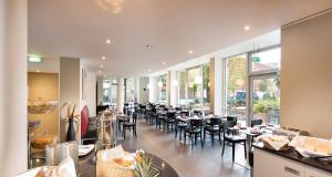 柏林泰格尔柏林胜利皇宫酒店的用餐室设有桌椅和窗户。