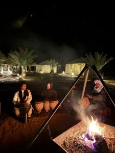 AdrouineNomads Luxury Camp Merzouga的一群人围坐在 ⁇ 火旁