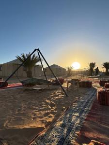 AdrouineNomads Luxury Camp Merzouga的海滩上的一个大物体,背景是日落