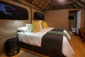 帕特森Elephants Safari Lodge - Bellevue Forest Reserve的一间卧室配有一张大床,提供黄色和绿色的枕头