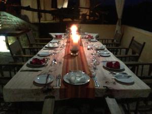 KikobogaMikumi Wilderness Camp的一张带蜡烛、盘子和银器的长桌