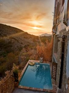 PatróCasa rural Vall de Gallinera con Chimenea, piscina y jacuzzi DIANIA的一座游泳池,位于一座享有日落美景的建筑旁边