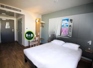 蒙特利马尔B&B HOTEL Montélimar Sud的卧室配有一张白色的大床和一张桌子
