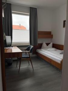 博尔库姆Hotel Passat的一间卧室配有一张床、一张书桌和一个窗户。