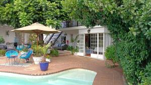 约翰内斯堡Darrenwood Guesthouse & SPA的一座带游泳池和遮阳伞的房子