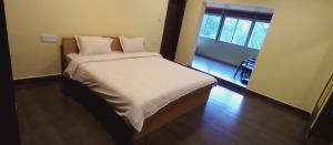 马西尼古蒂The Wild Fo'rest Resorts的一间卧室配有一张带白色床单的床和一扇窗户。