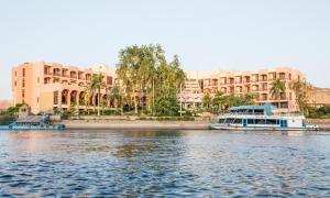 阿斯旺Pyramisa Island Hotel Aswan的大型建筑前的水面上的船