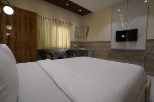 孟买Palm Springs Beach Resort - Gorai的卧室配有一张白色大床和电视。