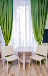 哈尔科夫Комфортная студия Вокзал Харьков-Пассажирский的一张桌子和两把椅子,配有绿色窗帘