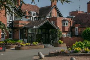 凯尼尔沃思Chesford Grange Hotel的一座大砖砌建筑,前面有植物