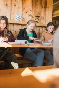 费马恩Büdlfarm - Der Familien-Erlebnishof in Strandnähe的坐在餐厅桌子上的三个女孩
